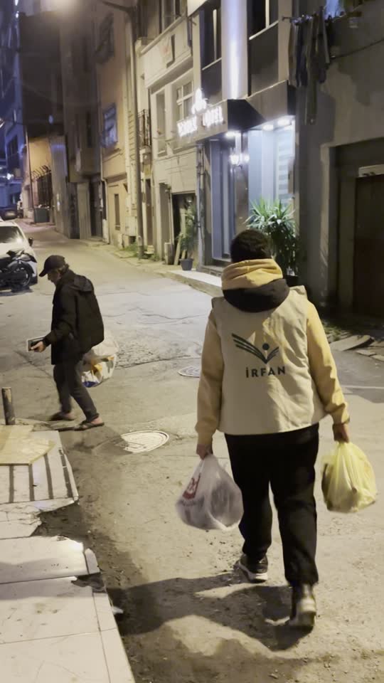 متطوع بسترة عرفان يحمل أكياس الوجبات إلى البيوت ليلًا